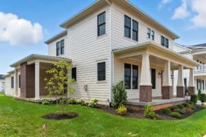Modern white two-story house with front porch and landscaped yard.