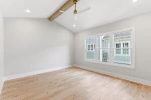 Bright living room with large windows, white walls, and light wood flooring.
