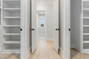 Open walk-in closet with built-in shelves and white doors.