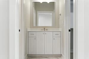 Modern bathroom vanity with mirror and white cabinetry in a new home.