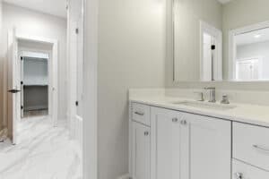 Bathroom vanity with mirror, sink, and white cabinets in a contemporary home.