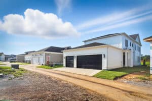 A new residential house with a three-car garage and white siding.