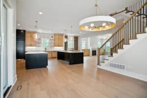 Spacious interior featuring a contemporary kitchen, hardwood floors, and staircase railing.