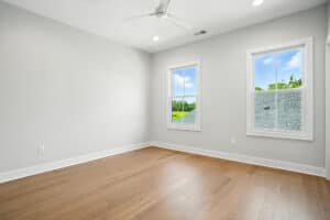 Empty bedroom with two windows and natural light in a new home.