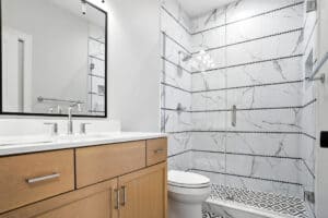 Bathroom with marble tiled shower and contemporary wooden vanity.