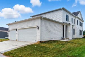 Bright exterior view of a new residential home with a spacious garage and well-maintained lawn.