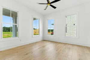 Spacious room with white walls, multiple windows, and a ceiling fan.