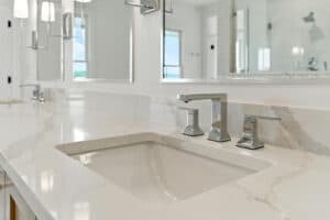 Bathroom sink with sleek faucet and marble countertop in a bright, modern bathroom.