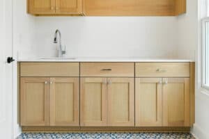 Cabinetry in a modern kitchen with natural wood finish and white countertop.